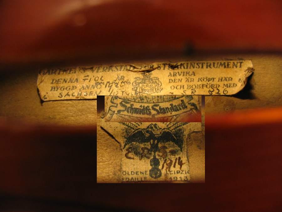 Denna fiol är importerad av Gärtners Verkstad för Sråkinstrument i Arvika, nr SR 826. Byggd omkring 1920 i Markneukirchen. Förmodligen vid Fabrik E.R. Schmidt & Co. (Ernst Reinhold Schmidt1857-1928). Delen med Schmidt Standard är ej komplett. Guldmedalj, Leipzig 1913, intressant kuriosa, bildmontage.

